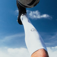 Person kicking a soccer ball against a blue sky
